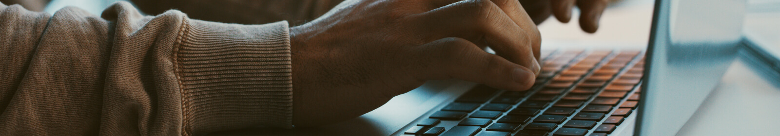 Close up of a person's hands using a laptop keyboard